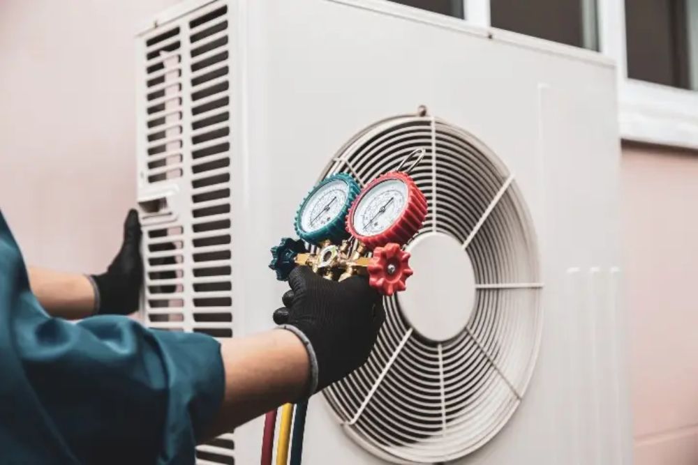 A man with a thermometer adjusts an air conditioner, showcasing heating and air conditioning repair in Spokane, WA.