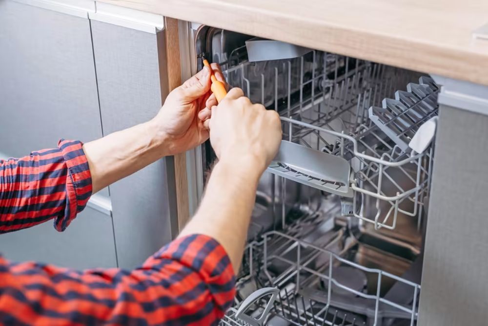 A technician works on fixing a dishwasher in a kitchen, highlighting appliance repair services in Spokane, WA.