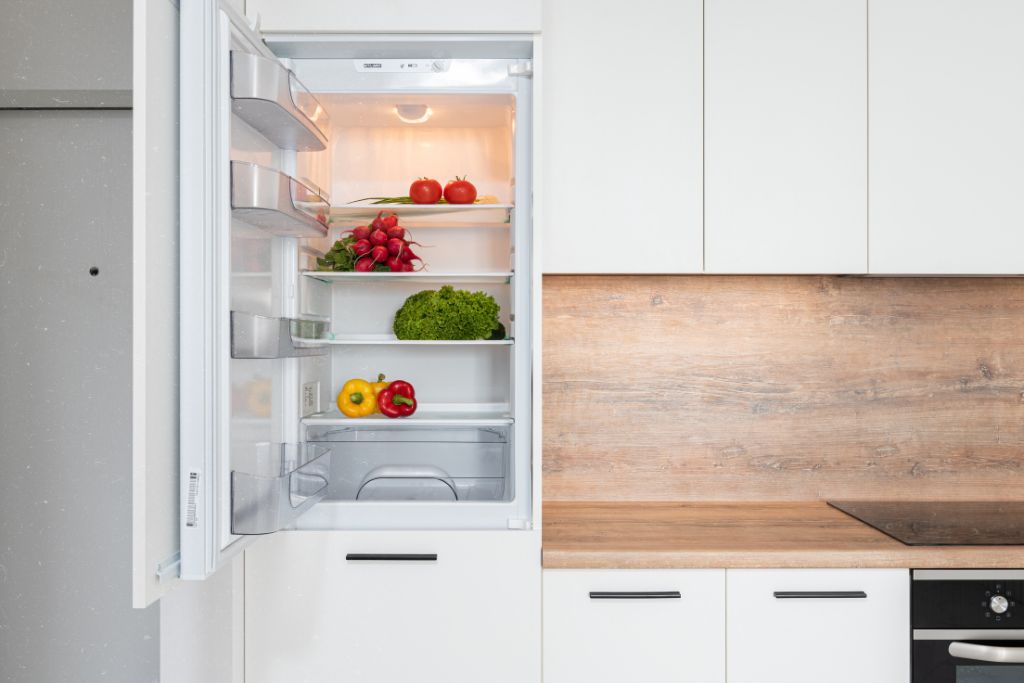 A refrigerator filled with an assortment of fresh vegetables and fruits, showcasing vibrant colors and healthy options.