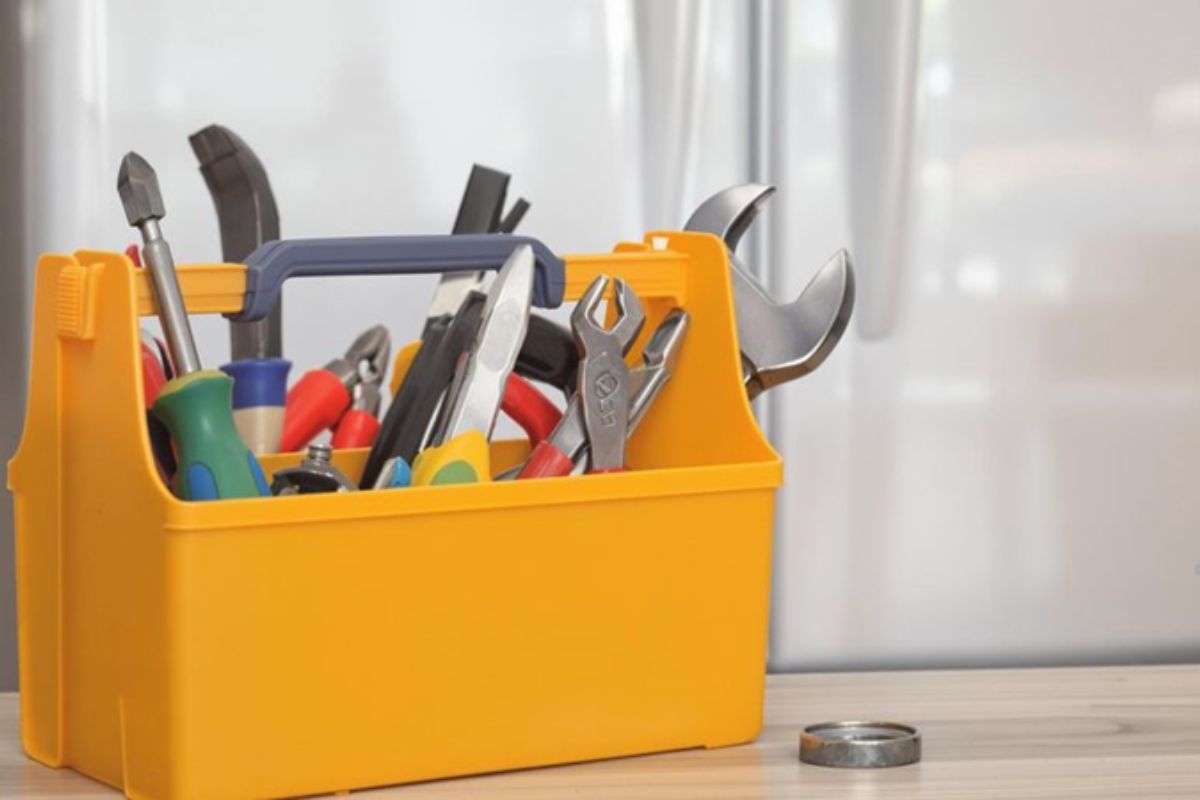A yellow toolbox filled with various essential tools for basic refrigerator repairs