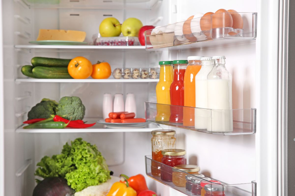 An open refrigerator displaying various food items, highlighting the need for appliance repair due to its disorganized state.