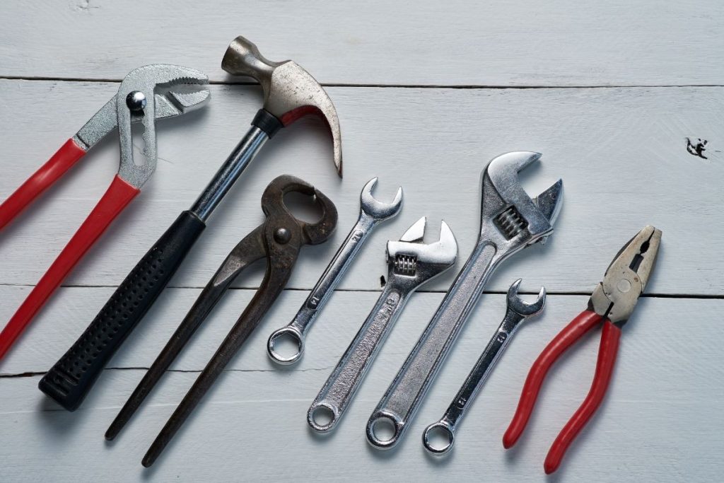 A variety of tools laid out on a white wooden table, emphasizing their unique forms and purposes.